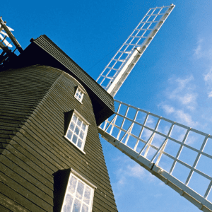 A skyward view showing the windmill's sails against a blue sky