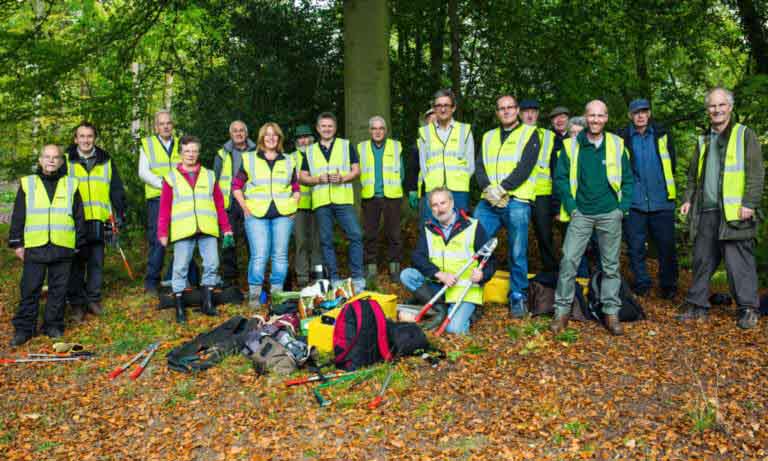 Twenty volunteers with their kit in the woods posing for the camera