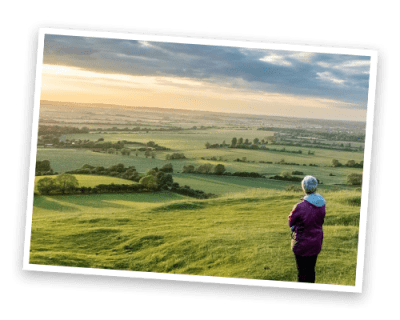 A person with their back to us looking out over the Chilterns landscape at sunset