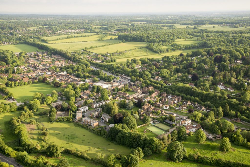 An aerial photo of a large village with fields and trees to the horizon