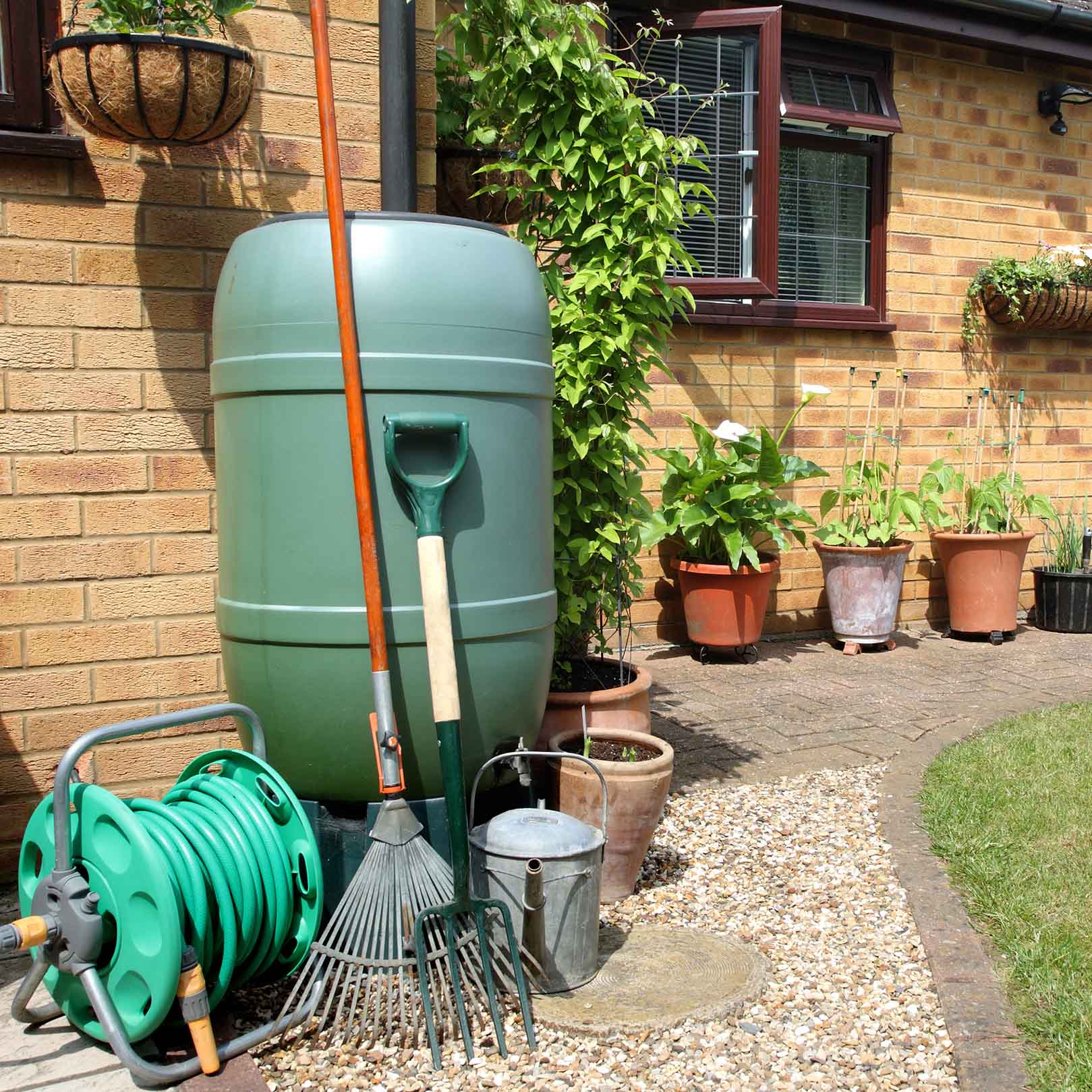 An English back garden with Water Butt, flowerpots, garden tools and Hose